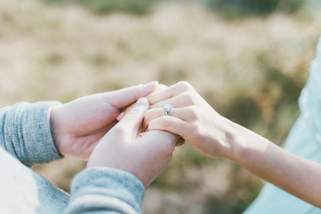 couple holding hands with the woman wearing an engagement ring